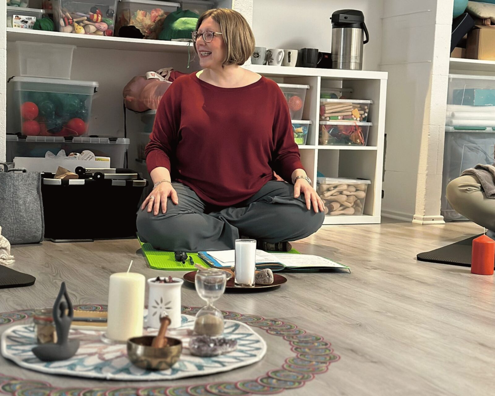 Kerstin Hiemer sitzt lächelnd im Schneidersitz und leitet einen früheren Rauhnächte-Workshop an